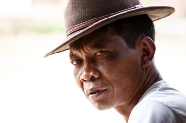 CHIN STATE, MYANMAR - JUNE 18 2015: Smart man in hat, sitting in the recently opened for tourists Chin State Mountainous Region, Myanmar (Burma)
