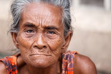 YANGON, MYANMAR - JUNE 12 2015: Older lady sits on the street on one of the hottest recorded days before monsoon season in Yangon, Myanmar.