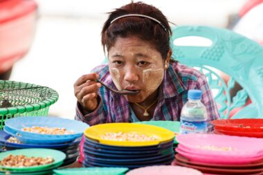 YANGON, MYANMAR - JUNE 12 2015: Local lady eats at market on one of the hottest recorded days before monsoon season in Yangon, Myanmar.