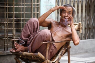 YANGON, MYANMAR - JUNE 12 2015: Old man smoking burmese cheroot cigar on one of the hottest recorded days before monsoon season in Yangon, Myanmar.