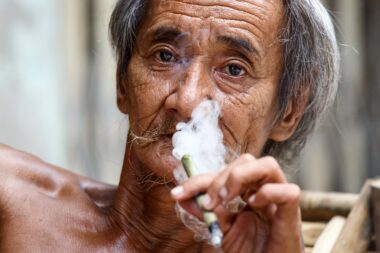 YANGON, MYANMAR - JUNE 12 2015: Old man smoking burmese cheroot cigar on one of the hottest recorded days before monsoon season in Yangon, Myanmar.